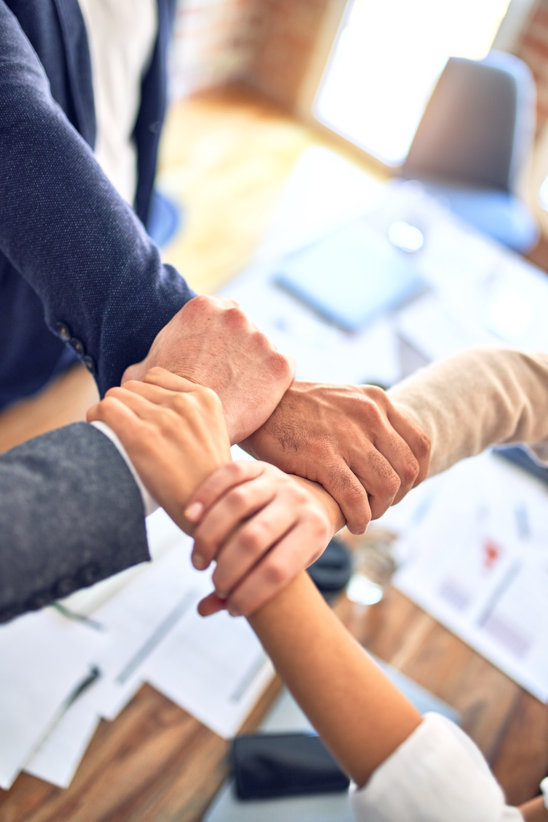 about Group of business workers standing with hands together doing symbol at the office