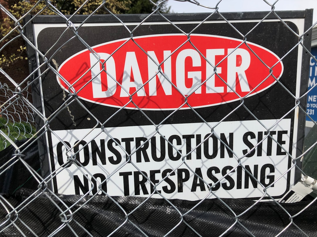 a sign on a fence that says danger construction site no trespassing
