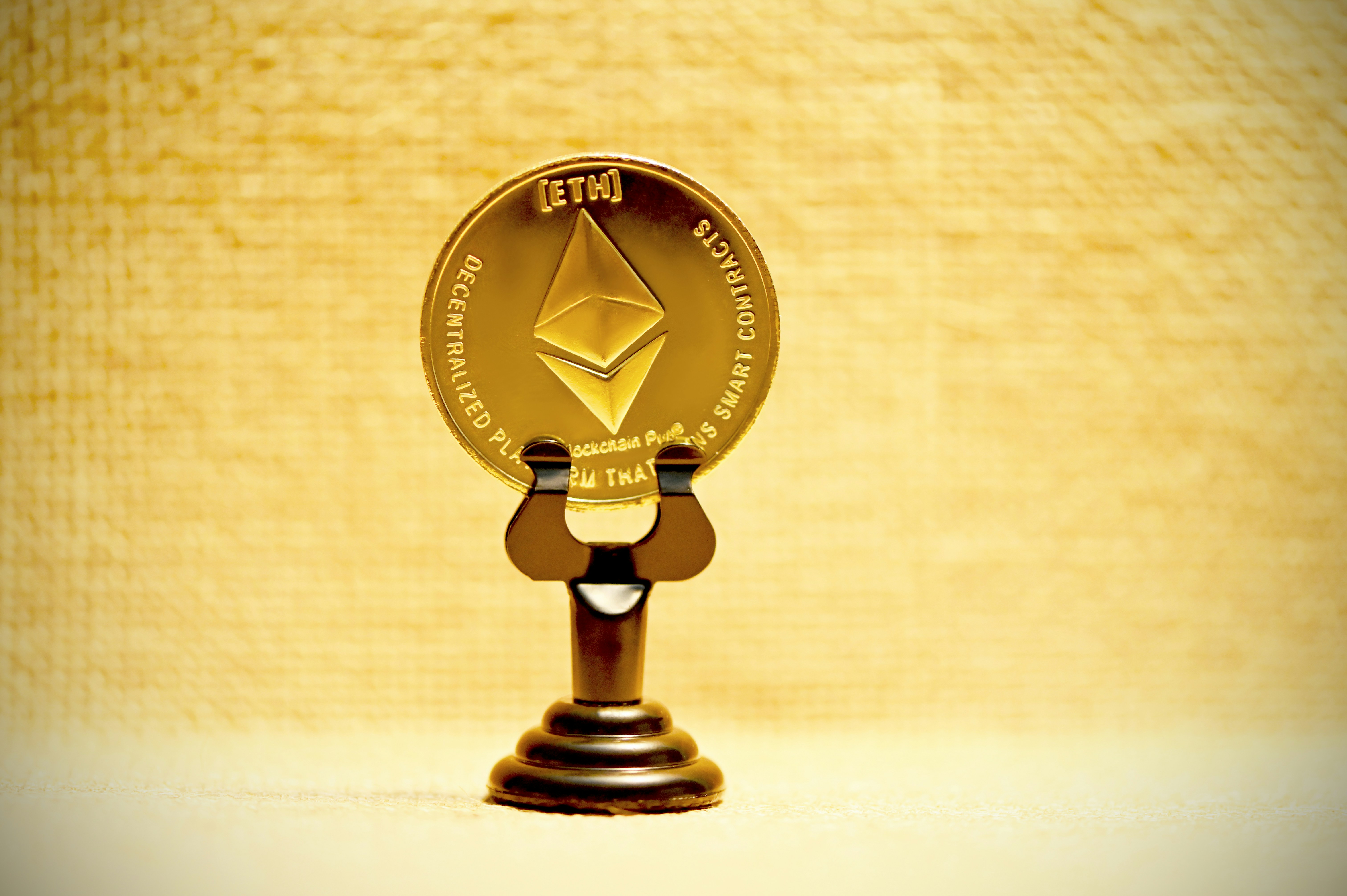 ETH coin stands alone by Popular Brands a gold ether coin on a wooden stand