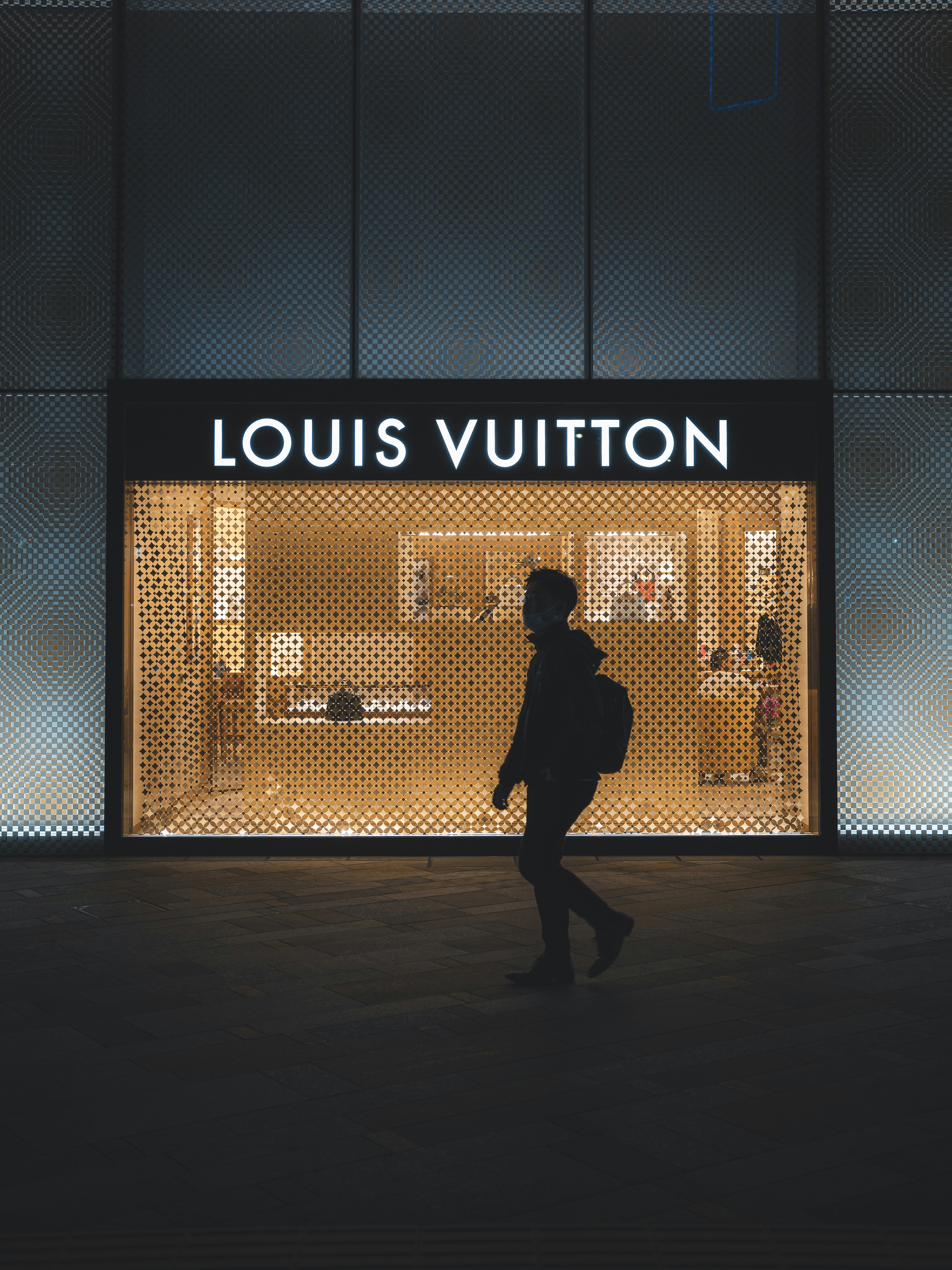 a person walking in front of a louis vuitton store